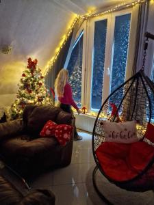 Ein kleines Mädchen steht in einem Wohnzimmer mit einem Weihnachtsbaum in der Unterkunft Home Belić Golija in Radaljica