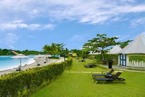 Natra Bintan, a Tribute Portfolio Resort في لاغوي: حديقة بها كراسي وطاولات وشاطئ