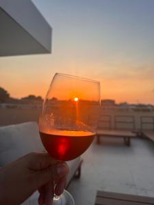 a person holding a glass of wine with the sunset in the background at Villa Santiago in Manaus