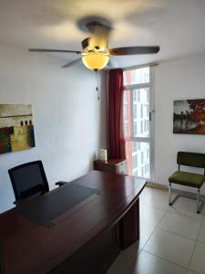 a desk in a room with a ceiling fan at Cute apartment 5min from the airport in Salsipuedes