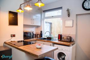 a kitchen with a sink and a washing machine in it at Liverpool City Grandeur by Sheryl - Close to City Center, Anfield Stadium and Airport with free business super fast fibre broadband in Liverpool