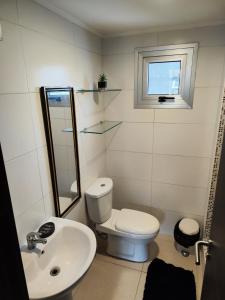 a white bathroom with a toilet and a sink at Cute apartment 5min from the airport in Salsipuedes