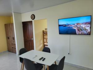 a dining room with a white table and a tv on a wall at Cabana Acunas House in Santa Marta +7 photos