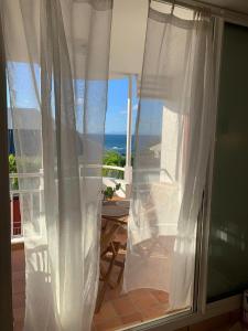 una ventana con cortinas blancas y vistas al océano en Studio Entre Terre et Mer, Tartane, Martinique, en La Trinité