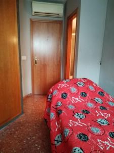 アルボラヤにあるHabitación individual con baño privado, Desayuno y piscinaの赤い掛け布団と木製のドアが備わるベッドルーム1室