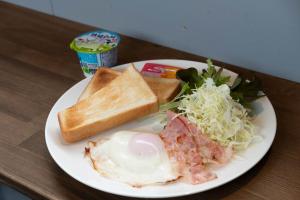 un plato blanco de comida con huevos pan y ensalada en ロッヂモントゼー, en Yuzawa