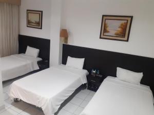 2 camas en una habitación de hotel con sábanas blancas en HOTEL DORAL, en Guayaquil