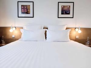 ゲランドにあるBest Western Hôtel De La Cité & Spaの白い枕付きの大型ベッド1台が備わります。