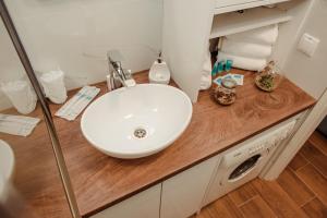La salle de bains est pourvue d'un lavabo blanc et d'un comptoir en bois. dans l'établissement Passage apartment Subotica, à Subotica
