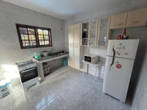 W kuchni znajduje się biała lodówka i kuchenka mikrofalowa. w obiekcie Casa na esquina da praia com quintal w mieście Saquarema
