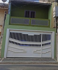 uma porta de garagem branca num edifício verde em Casa para 12 pessoas perto da Basílica e da Feira em Aparecida