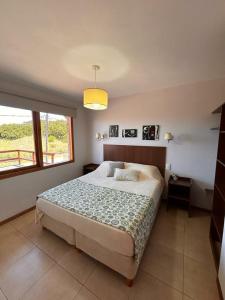 1 dormitorio con cama grande y ventana grande en Cabañas Agreste en Villa Gesell