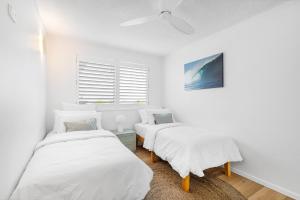 a white room with two beds and a window at Maroochydore Beachfront in Maroochydore