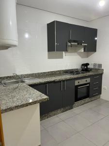 eine Küche mit schwarzen Schränken und einem Waschbecken in der Unterkunft Bel appartement in Tangier