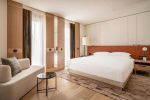 een slaapkamer met een groot wit bed en een bank bij Munich Marriott Hotel City West in München