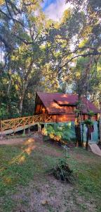 a wooden cabin with a bridge in a forest at Ecos da Terra Chalés in Monte Verde