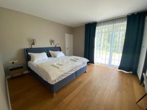 1 dormitorio con cama y ventana grande en Apartamentai Ornamentai en Druskininkai