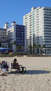 een vrouw in een stoel op het strand bij Apartamento beira mar na Praia Guilhermina,ambiente familiar in Praia Grande