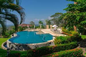 a swimming pool in a yard with flowers and plants at Residence Nativa Las Vistas, appartement in Tarcoles