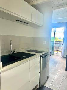 a white kitchen with a sink and a dishwasher at Duplex Marina gosier- vue Mer et bateaux in Le Gosier