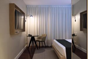 um quarto de hotel com uma cama e uma mesa e cadeira em HIGI HOTEL SÃO PAULO em São Paulo
