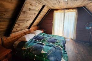 1 dormitorio con 1 cama en una cabaña de madera en Cabañas La Mano Puimayen Cabaña Grande l Reserva con Seña en Barra del Chuy