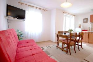 ein Wohnzimmer mit einem roten Sofa und einem Tisch in der Unterkunft Apartments with a parking space Njivice, Krk - 21773 in Njivice