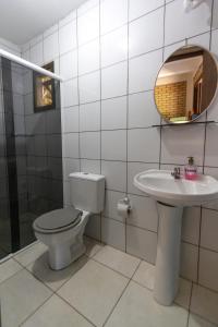 a bathroom with a toilet and a sink at Paraíso Hostel Praia do Rosa in Praia do Rosa