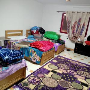 een kamer met drie bedden en tapijten op de vloer bij بيت الطالبات والمغتربات in Zes oktober (stad)