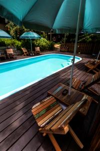 uma piscina com uma cadeira e um guarda-sol em Paraíso Hostel Praia do Rosa na Praia do Rosa