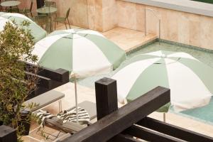 two green and white umbrellas in a swimming pool at Hotel Sorrento in Sorrento