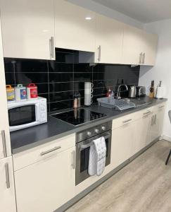 a kitchen with white cabinets and a stove and microwave at Mediacity studio apartment Salford-quays in Manchester