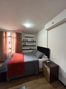 a bedroom with a bed with a red and gray blanket at Flat em Brasília - Park Sul in Brasília