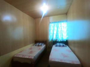 two beds in a small room with a window at Mabul Backpackers in Pulau Mabul 