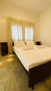 a bedroom with two beds with white sheets and a window at Fairline Gardens Hiriketiya in Dickwella