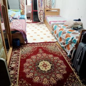 a room with two beds and a rug on the floor at بيت الطالبات in 6th Of October