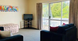 a living room with a couch and a tv and a window at Caves Motor Inn in Te Kuiti