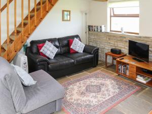 a living room with a leather couch and a television at The Byre in Broom