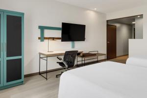 a bedroom with a bed and a desk with a television at Courtyard by Marriott San Jose Airport Alajuela in Alajuela City