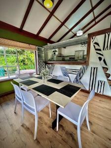 a dining room with a table and white chairs at Cabaña Río Blanco Guapiles Costa Rica in Guápiles