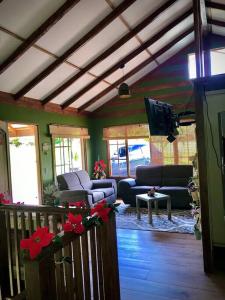 a living room with couches and a flat screen tv at Cabaña Río Blanco Guapiles Costa Rica in Guápiles