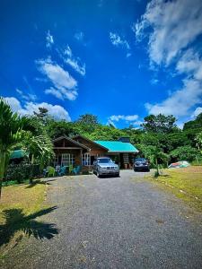 ein Haus mit zwei Autos, die davor geparkt sind in der Unterkunft Cabaña Río Blanco Guapiles Costa Rica in Guápiles