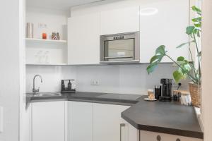 a kitchen with white cabinets and a microwave at Untersee-Suite IStayUnixI Seenähe-Terrasse-Workspace-Netflix-Parkplatz in Radolfzell am Bodensee