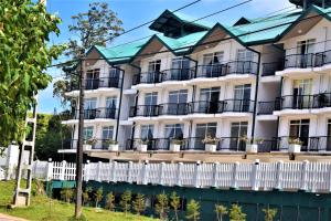 a white building with balconies and a fence at Infinity Condos by Lake Infinity in Nuwara Eliya