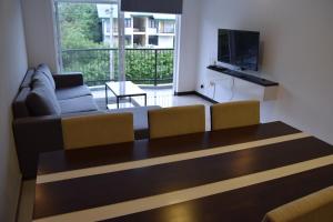 a living room with a couch and a television at Infinity Condos by Lake Infinity in Nuwara Eliya