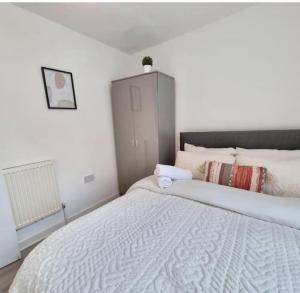 a white bedroom with a large bed and a cabinet at Anfield 5 minutes walk sleeps 10 in Liverpool