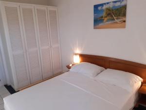 a bedroom with a white bed with a light on it at MANBANA 320 RESIDENCE KAWANN in Grand-Bourg