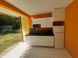 a kitchen with white appliances and an orange wall at MANBANA 320 RESIDENCE KAWANN in Grand-Bourg