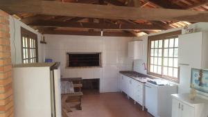 uma cozinha com armários brancos e uma parede de tijolos em Sitio do Espigão em Viamão