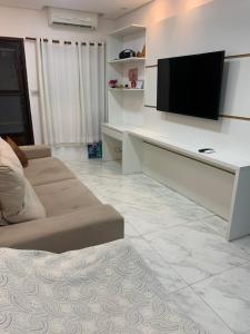 a living room with a couch and a flat screen tv at Casa com churrasqueira Guilhermina Praia Grande in Praia Grande
